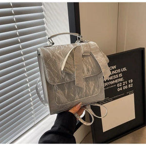 Detailed view of silver metallic wrinkled texture and bow decoration on the handbag