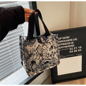 Detail of knit tote bag showing black butterfly patterns and floral print texture