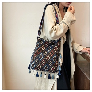 Detail of bohemian tote featuring geometric woven patterns and vibrant blue tassels