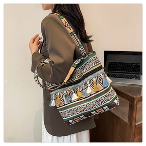 Close-up of bohemian woven tote bag featuring colorful geometric patterns and cotton tassels