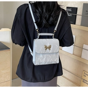 Vue arrière du mannequin portant le mini sac à dos gris clair à boucle papillon dorée
