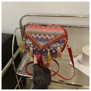 Detail view of heart-shaped woven bag with colorful geometric patterns and long tassels