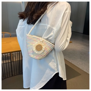 Close-up of woven bucket bag featuring colorful stitching and a white daisy floral detail