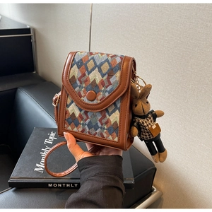 Detailed view of brown quilted crossbody bag featuring a plush rabbit pendant and snap closure