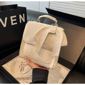 Detail of a creamy white crossbody bag with marble texture and a large ribbon bow