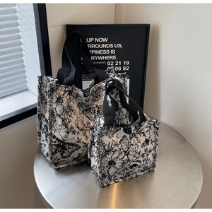 Detailed close-up of two retro floral knit tote bags in various sizes on a metal table