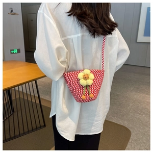 Detail of red and white woven crossbody bag with a 3D yellow sunflower and long strap