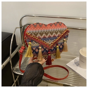Close-up of heart-shaped woven bag featuring ethnic patterns and tassel details