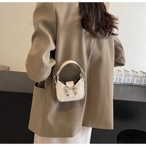 Detailed side view of a mini off-white bow handbag with a silver chain on a female model
