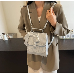 Detail of silver metallic backpack with bow decoration and crinkled texture surface