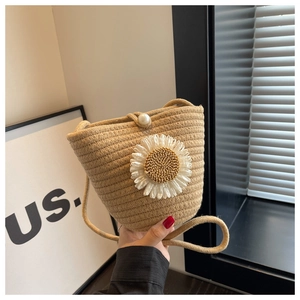 Detail of hand-woven bucket bag with daisy ornament and pearl buckle closure
