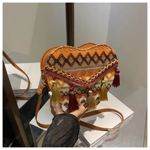 Close-up of heart-shaped bohemian woven bag with colorful tassels and leather strap