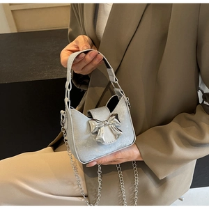 Detail of silver mini bag featuring a large mirror-finish metal bow and chain strap