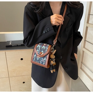 Vertical woven crossbody bag with brown leather trim and a cute plush rabbit charm