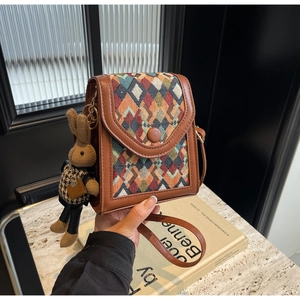 Detail of vertical crossbody phone bag with geometric patterns and cute bunny charm
