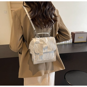 Close-up of silver crinkled metallic mini backpack with large bow detail on a model