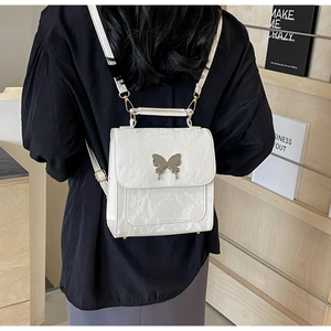 Vue détaillée du sac à dos blanc plissé avec pendentif papillon argenté sur modèle