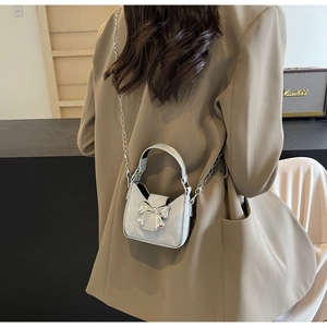 Close-up of mini silver glitter handbag with mirror bow and metallic chain strap