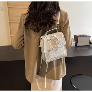 Silver wrinkled texture backpack with a large bow detail shown on a model in a studio