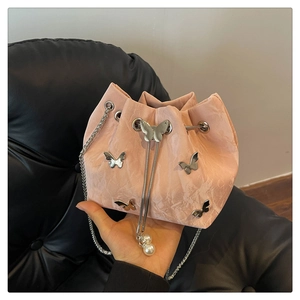 Detailed shot of pink pleated bucket bag with silver butterfly charms and pearl drawstring