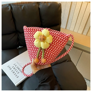 Detail of hand-woven bucket bag with red and white houndstooth pattern and yellow flower charm