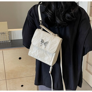 Détail du sac bandoulière en cuir froissé blanc cassé avec papillon argenté