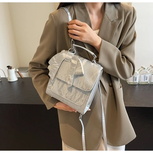 Silver metallic shoulder bag with bow detail and metal handle on a wooden table