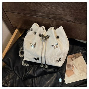 Detail of white drawstring bucket bag with metal butterflies and pearl drawstring accents