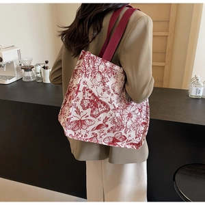 Detail of knit tote bag featuring red butterfly prints and sturdy ribbon handles