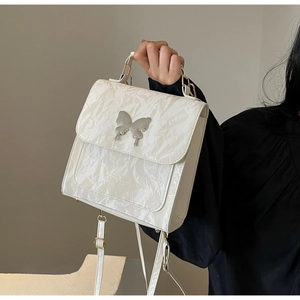 Détail d'un sac à main blanc en simili cuir brillant avec boucle papillon et anse supérieure