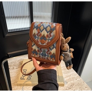 Vertical crossbody phone bag with colorful geometric patterns and plush bunny charm
