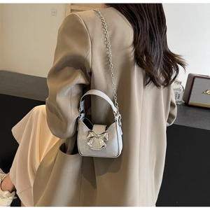 Detail of silver mini crossbody bag featuring metallic bow clasp and delicate chain strap