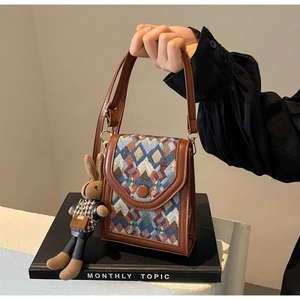 Detailed close-up of retro plaid crossbody bag with a cute rabbit doll charm accessory