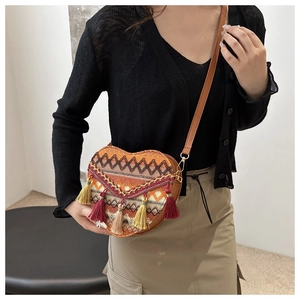 Detail view of woven heart-shaped crossbody bag with vibrant fringe and ethnic patterns
