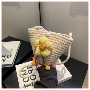 Detail of white straw bucket bag featuring colorful wave patterns and yellow flower charm