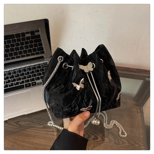 Detail of black velvet bucket bag featuring silver butterflies and pearl drawstring accents