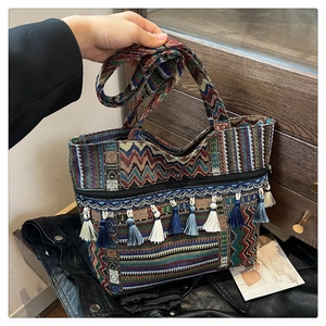 Macro view of ethnic woven tote bag featuring colorful geometric patterns and blue tassels