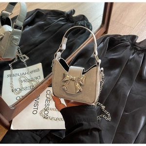 Macro view of silver glitter mini handbag featuring metallic bow buckle and chain strap