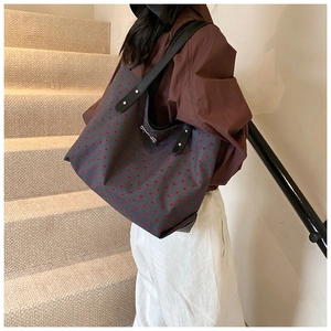 Detail of grey canvas tote bag with red heart pattern and black leather handles