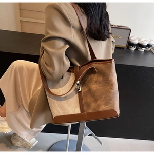 Detail of canvas leather tote bag featuring a metal buckle lock and vintage contrast design