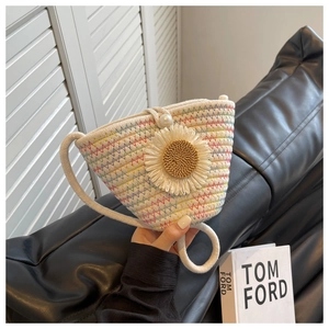 Detail of cream hand-woven bucket bag featuring rainbow stitching and daisy flower ornament