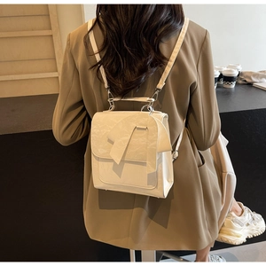 Fashionable beige backpack with large bow detail shown on model in urban setting