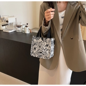 Detail of knit tote bag featuring black and white vintage floral and butterfly patterns