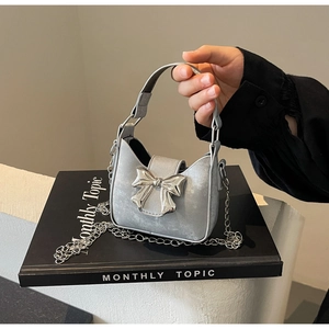 Detail of silver mini bag featuring a metallic bow buckle and chic chain strap