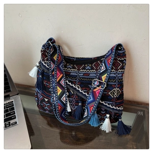 Detail of bohemian tote bag with geometric patterns, blue tassels, and wide shoulder strap