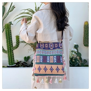 Detailed side view of a bohemian tote bag with colorful tassels and geometric patterns