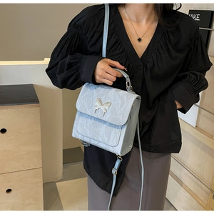 Détail du sac à main bleu clair plissé avec boucle papillon argentée et bandoulière