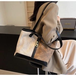 Detail of color-block tote bag with beige canvas, leather trim, and golden buckle