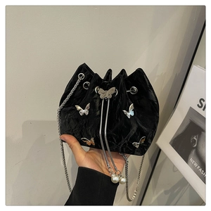 Detail of black velvet bucket bag featuring silver metal butterflies and pearl drawstring