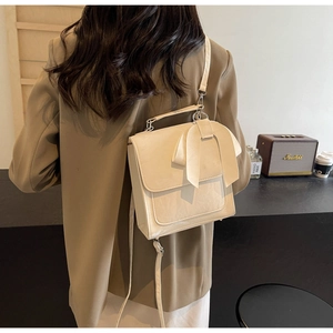 Detail of cream bow shoulder bag with textured finish shown in a lifestyle setting
